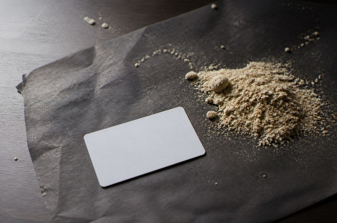 Pile of pale blonde static sift hash on dark parchment with a card