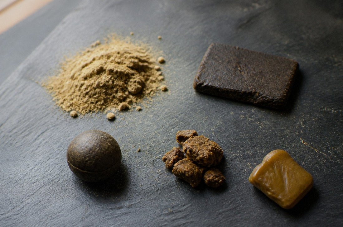 Five hash forms on slate: kief, pressed slab, temple ball, bubble hash and rosin